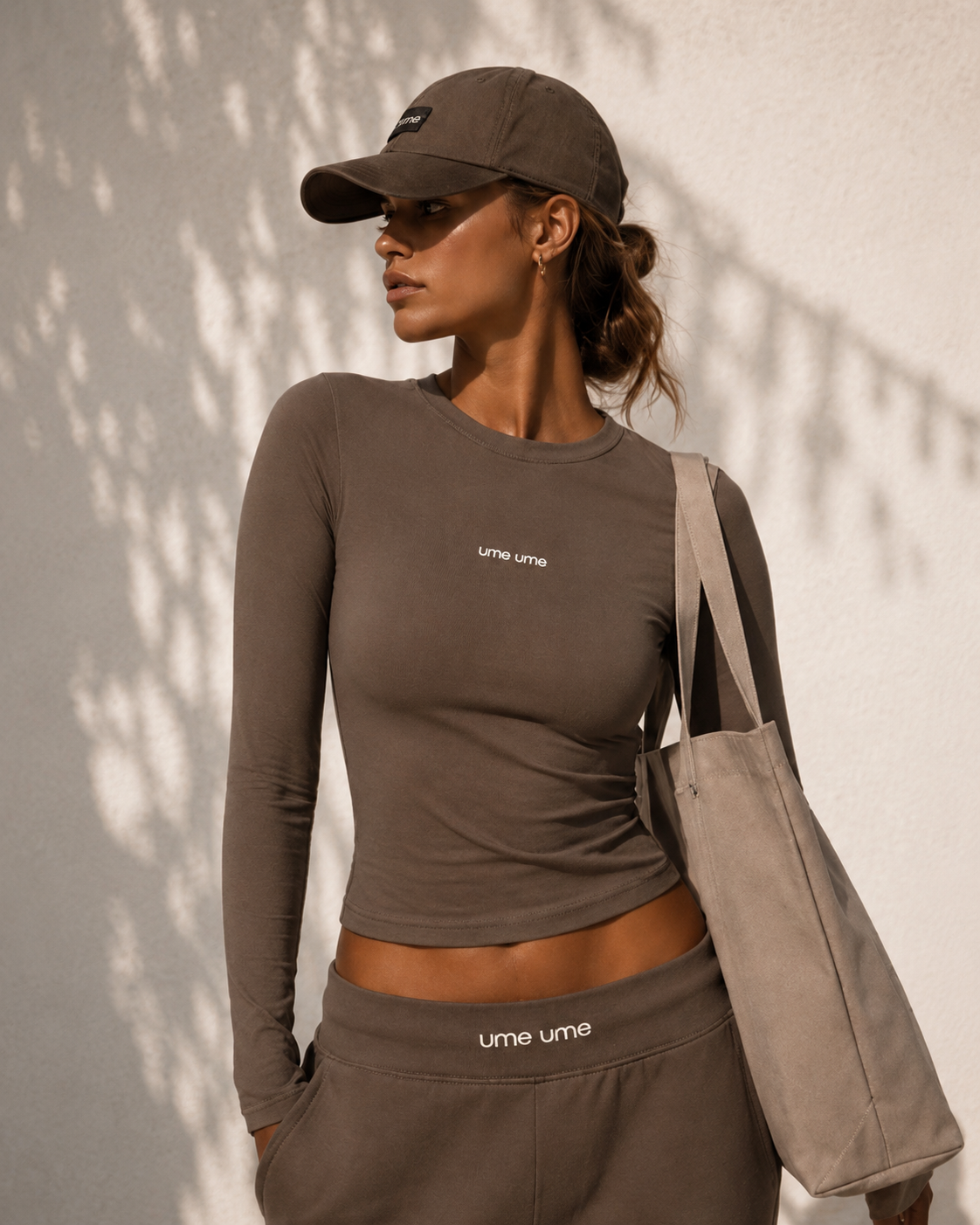 Editorial portrait of a woman in a taupe ume ume long sleeve and cap